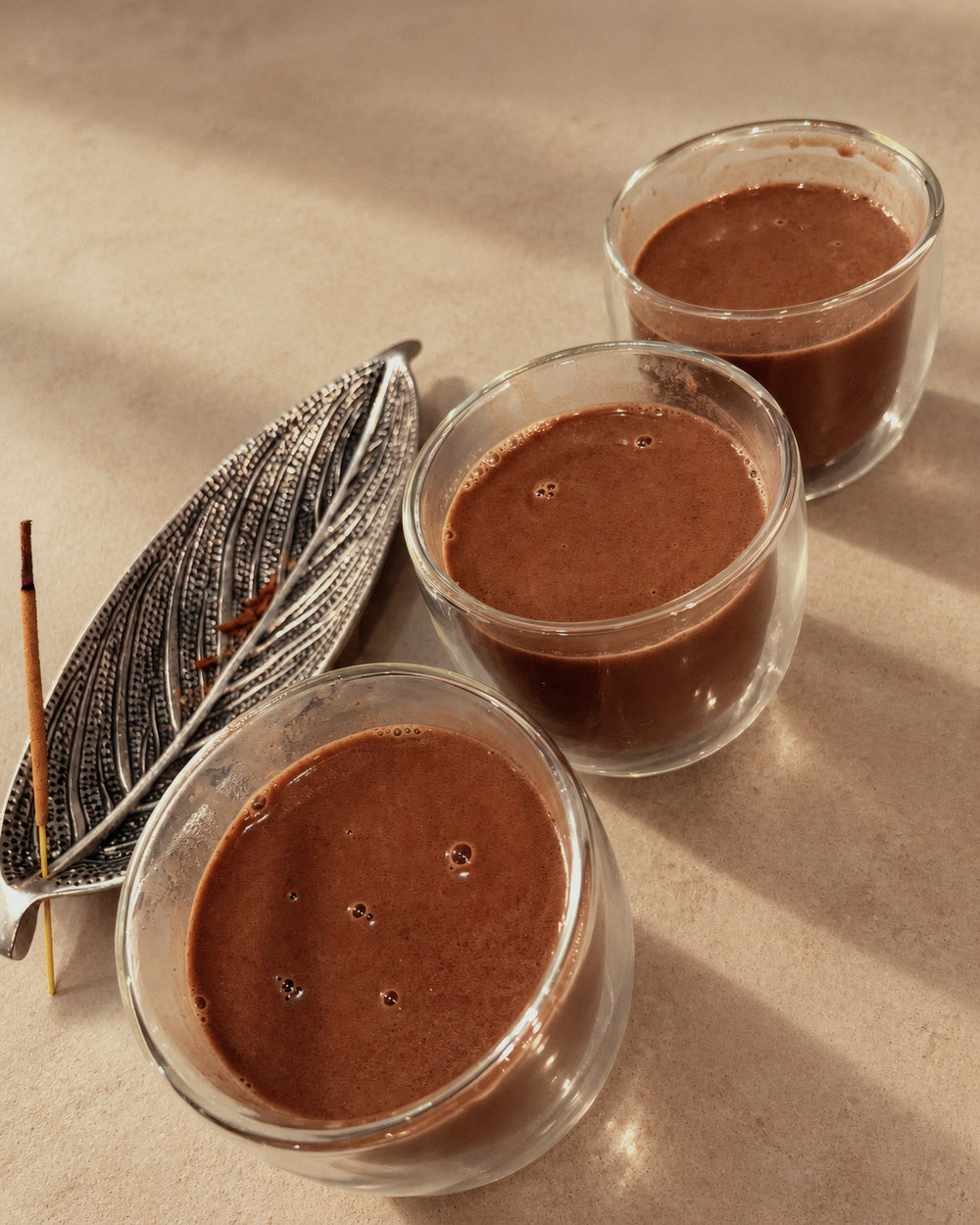 Three glasses of ceremonial cacao, blended until frothy