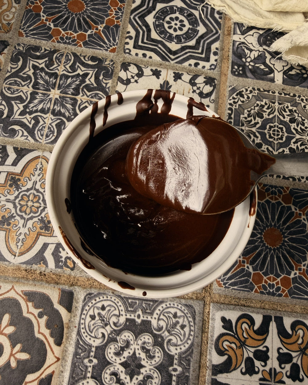 Glossy ground cacao in a bowl, lifted with a spoon
