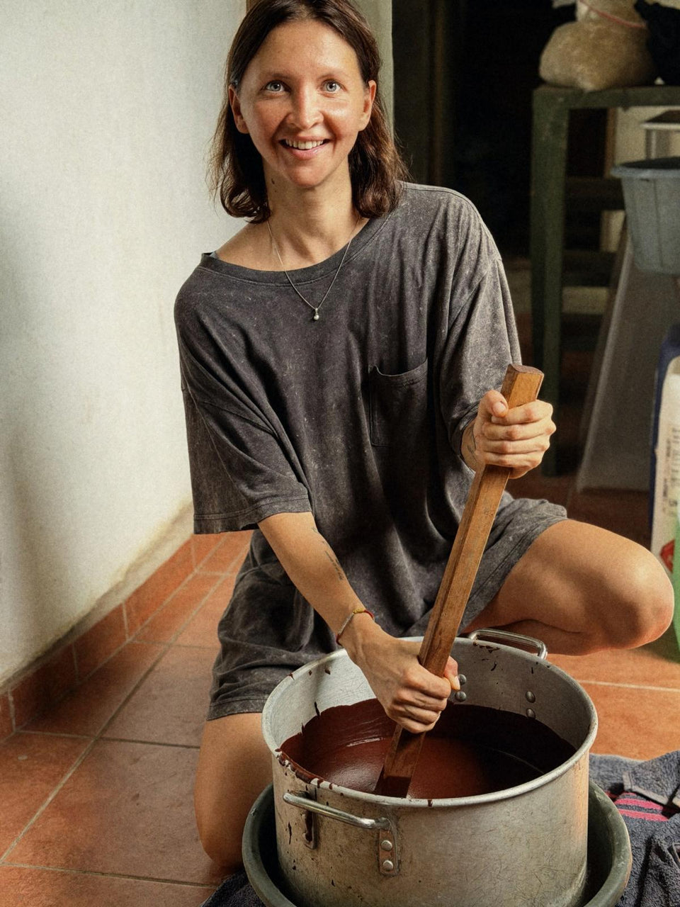 Katya stirring melted cacao in a large pot in the workshop