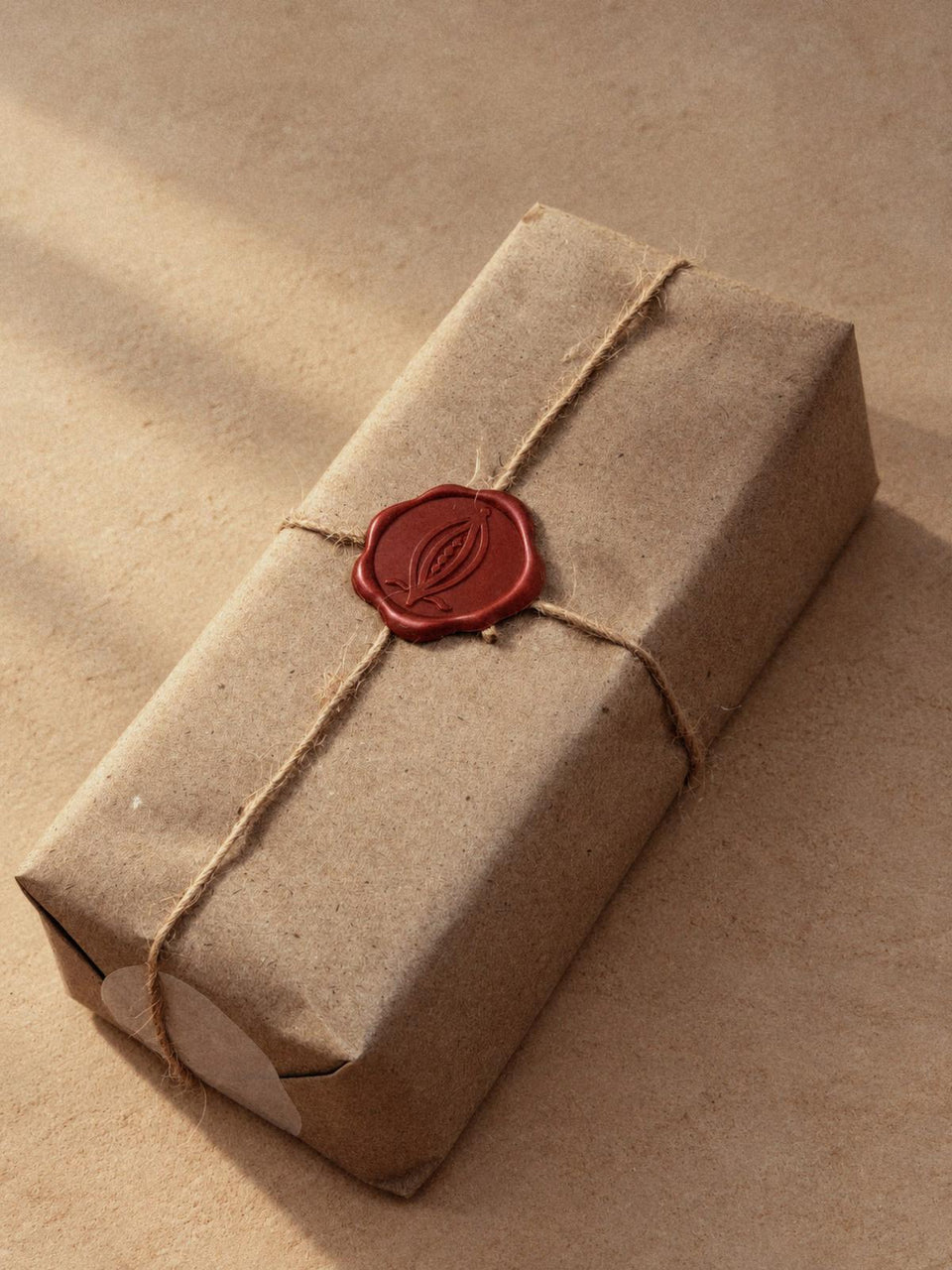 A cacao block wrapped in kraft paper and twine, closed with a red wax seal